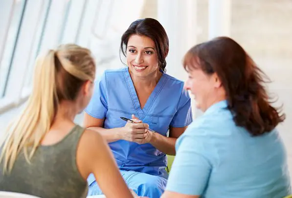 A group of women sitting around talking to each other.