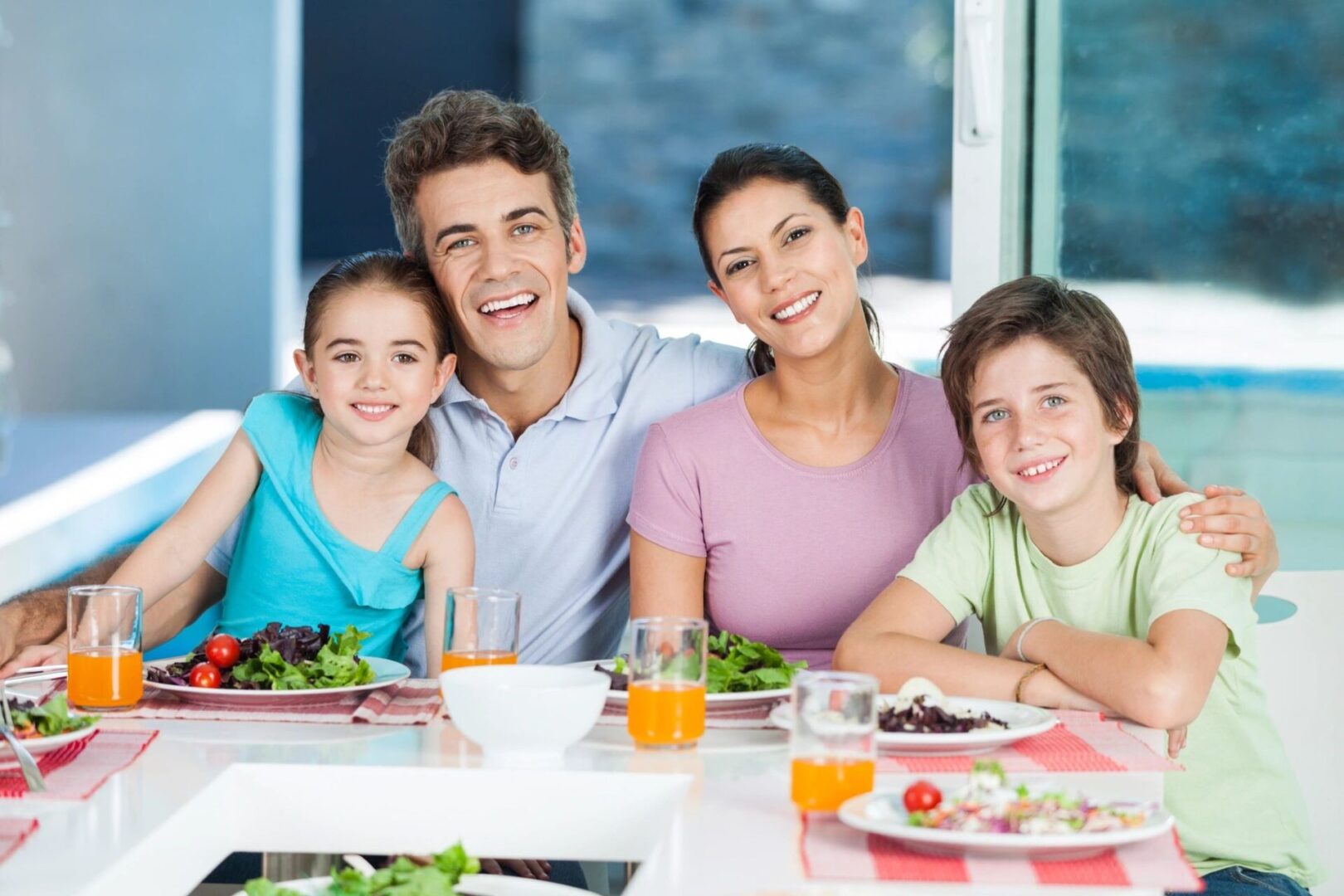 A family sitting at the table with plates of food.